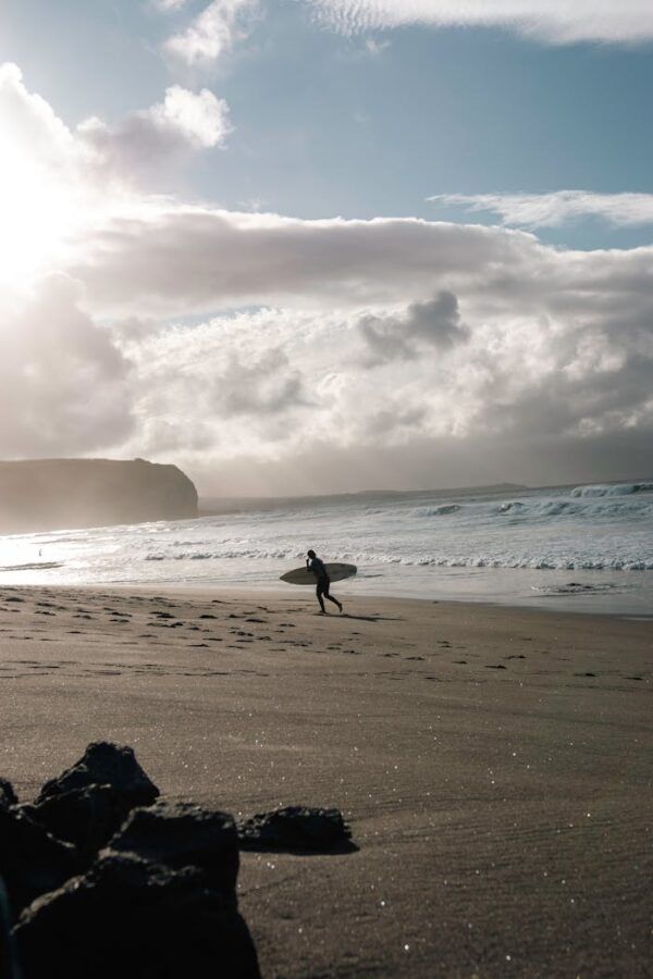 A surfer walks on the beach with a surfboard